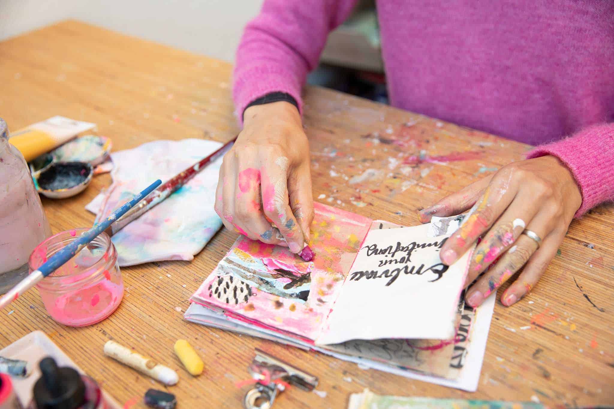 Aufgeschlagenes Art Journal, indem mit Buntstift gemalt wird 