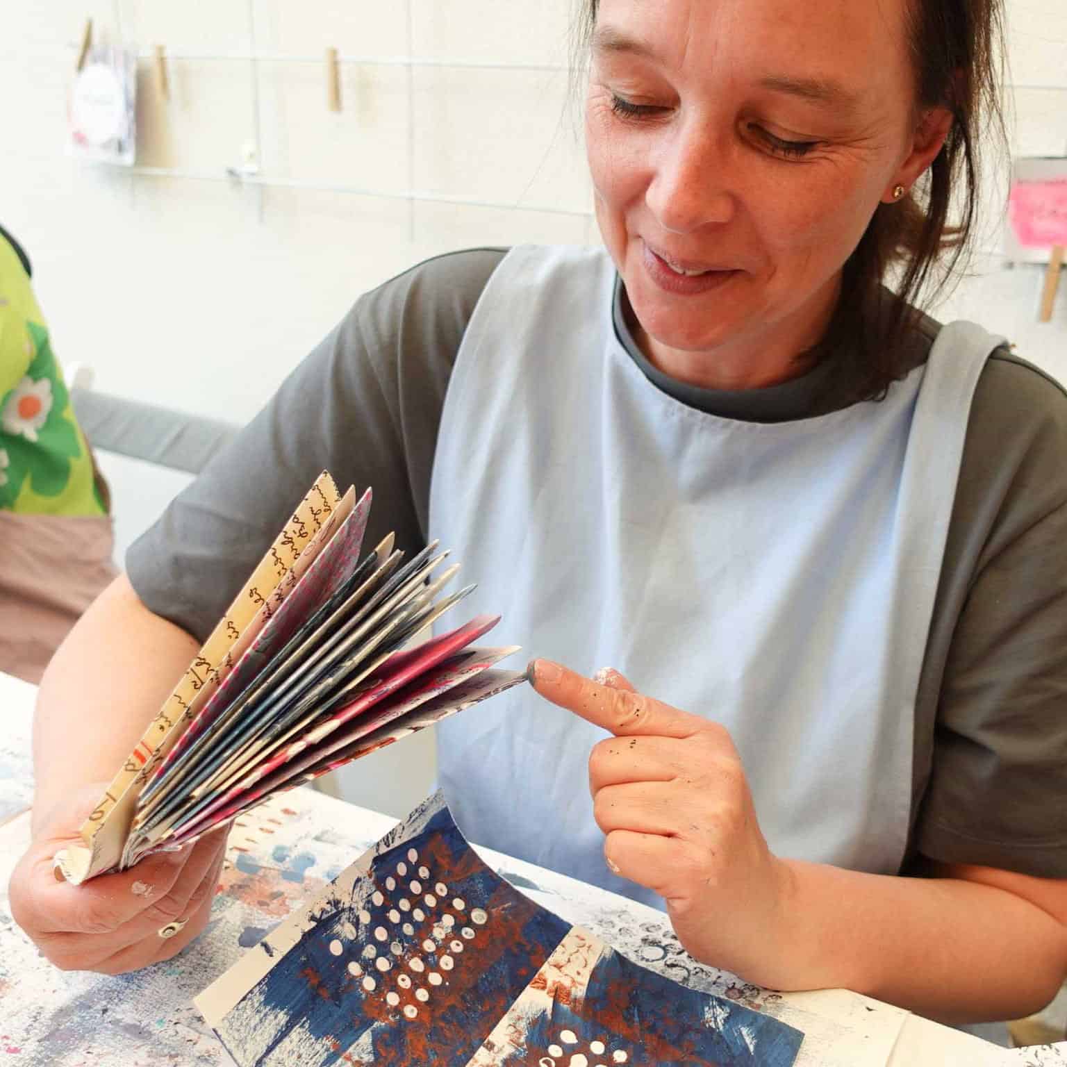 Workshop Teilnehmerin mit einzelnen Seiten ihres Art Journals im Mara Kreativstudio