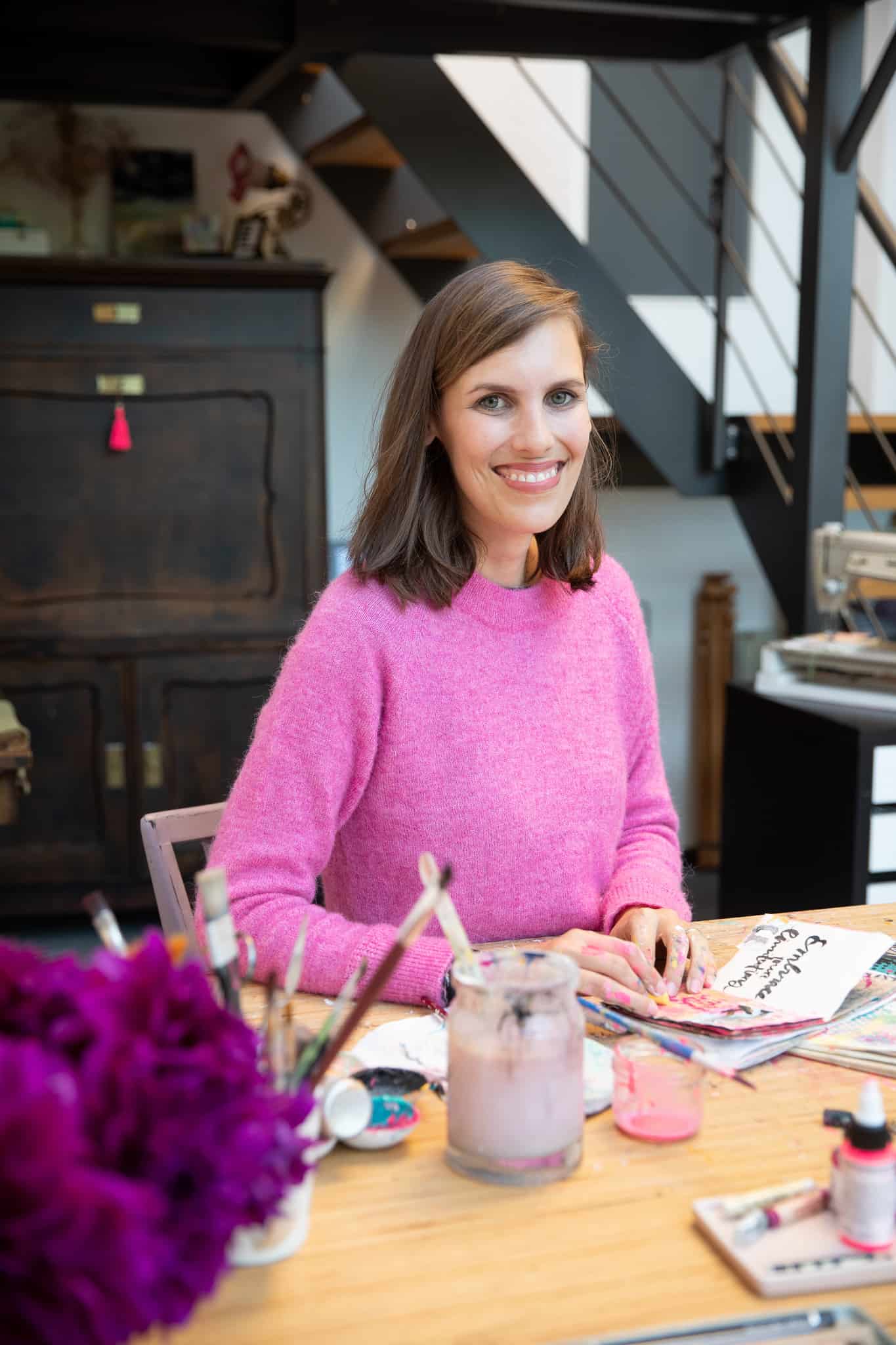 Portrait von Tamara Egem im Kreativstudio sitzend an ihrem Maltisch